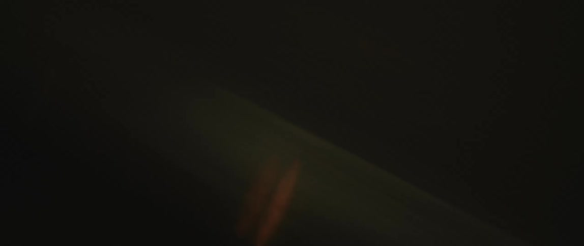 A vehicle speeds down a dark road at night