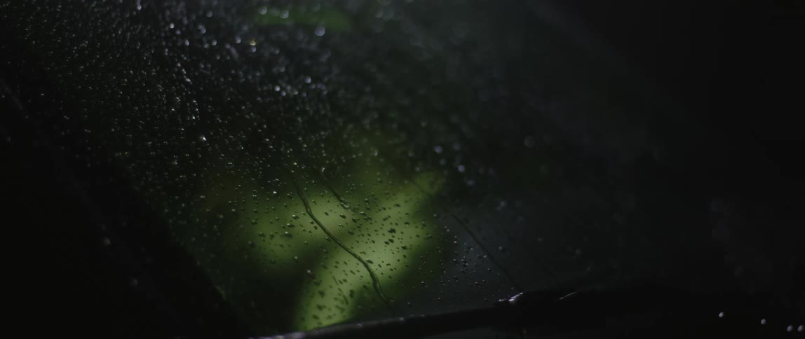 Water droplets running down the windshield of a car at night