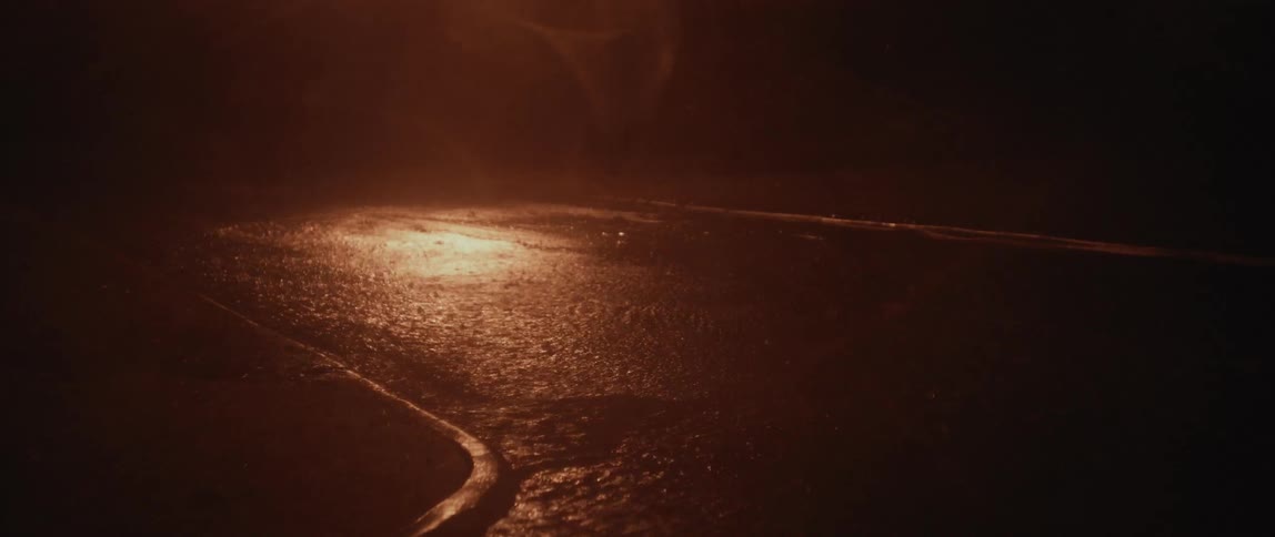 It is raining hard outside in the streets around night time