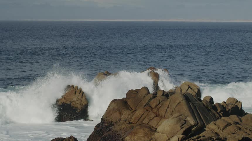Ocean waves break against the rocks on the shore