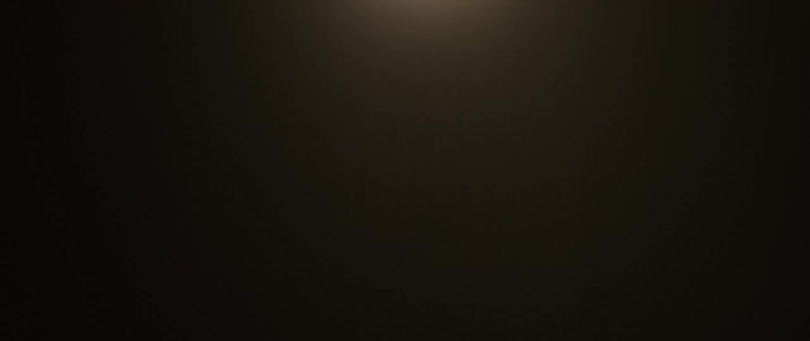 A warm yellow light shines down on a dim room