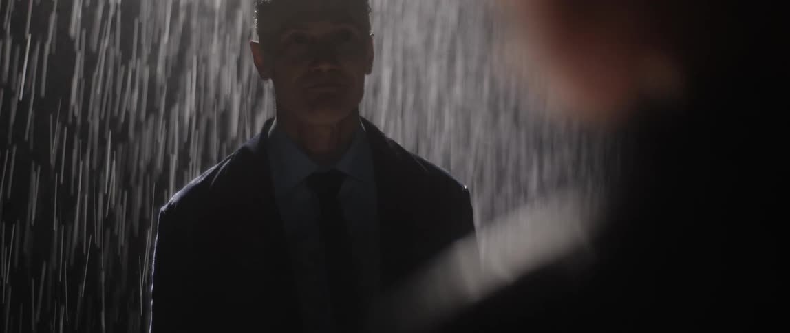 There are two men standing outside in the rain at night time