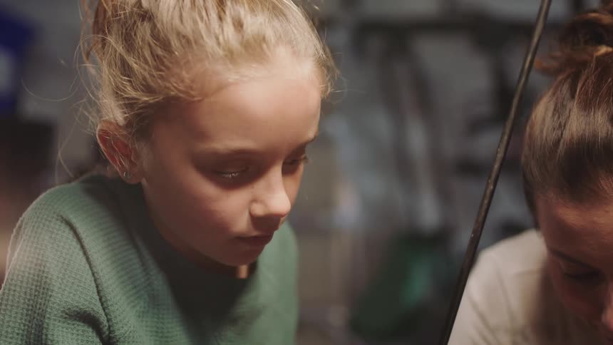 Mother teaching daughter about car engines in the garage at home