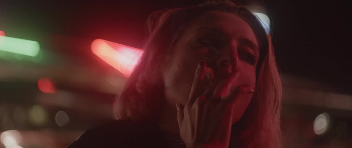 A young white woman is smoking a cigarette outside