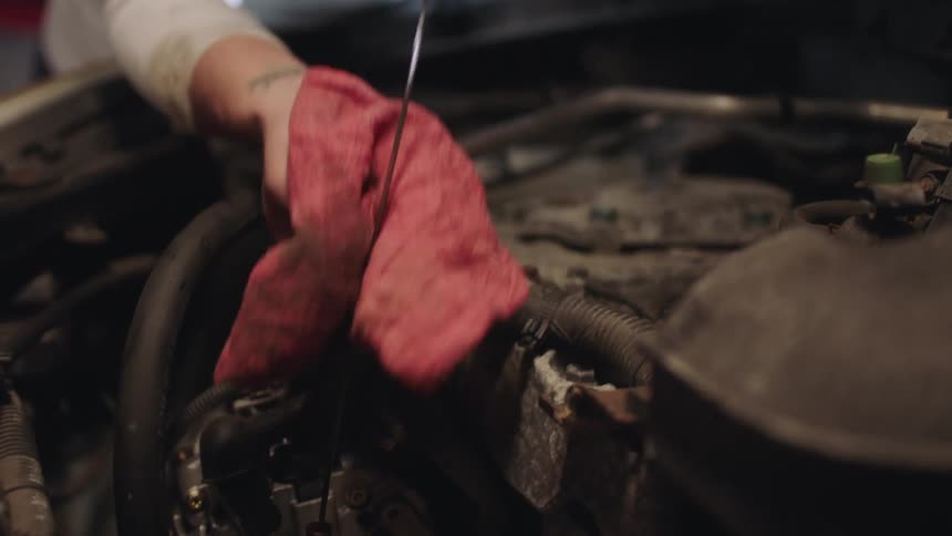 Close up of a mother teaching her daughter how to check the oil on the car
