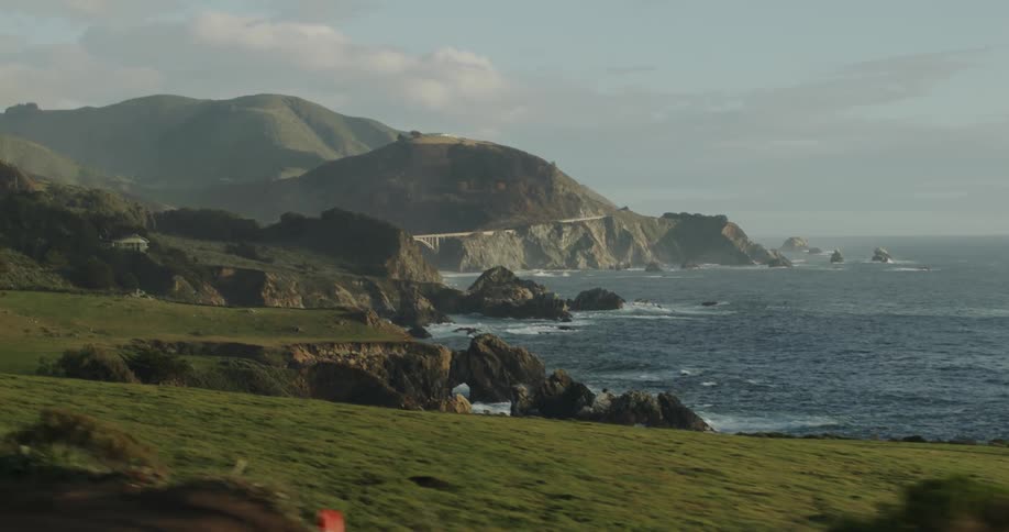 Cliffs on the coast next to the ocean seen from a moving vehicle at evening