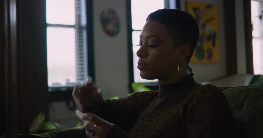 A woman is sitting on a couch and putting in headphones