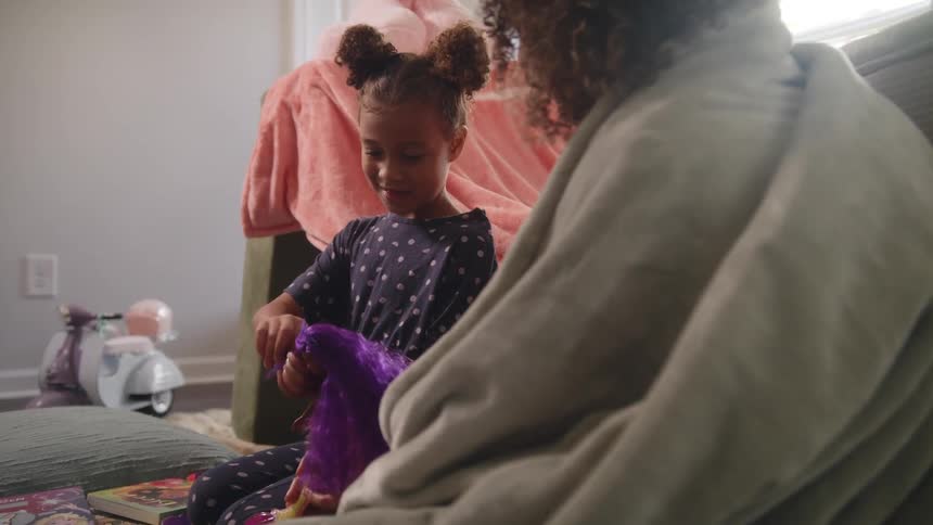 Mother and daughter sitting on the floor of the living room playing with a doll