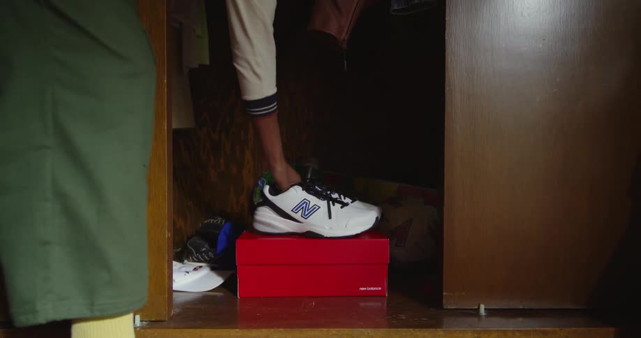 Woman picks up a pair of sneakers spinning over a shoe box inside a closet at home