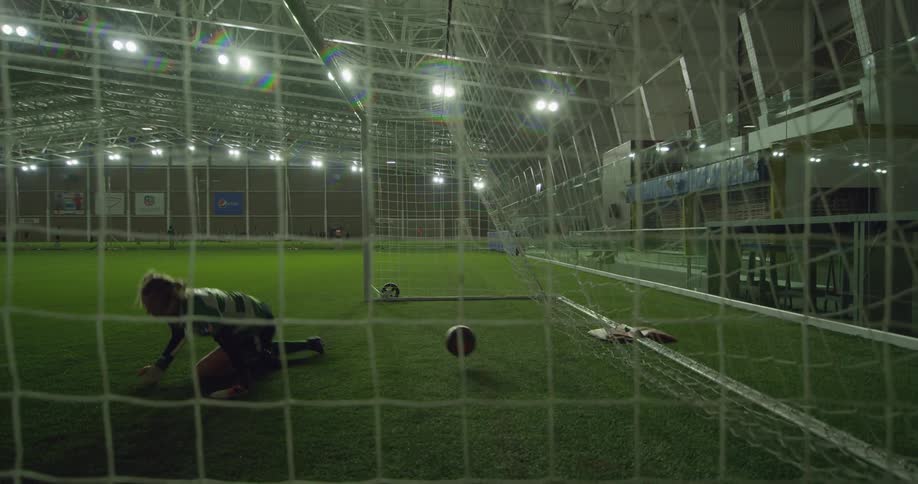 Woman playing soccer on a stadium scores a goal