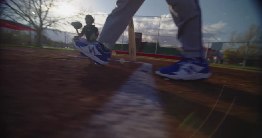 A batter walks to homeplate as a catcher squats ready for a pitch in a baseball game