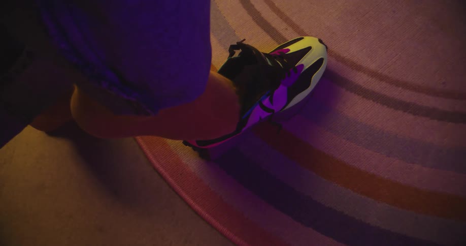 A person puts their foot down into a shoe that is on a rug