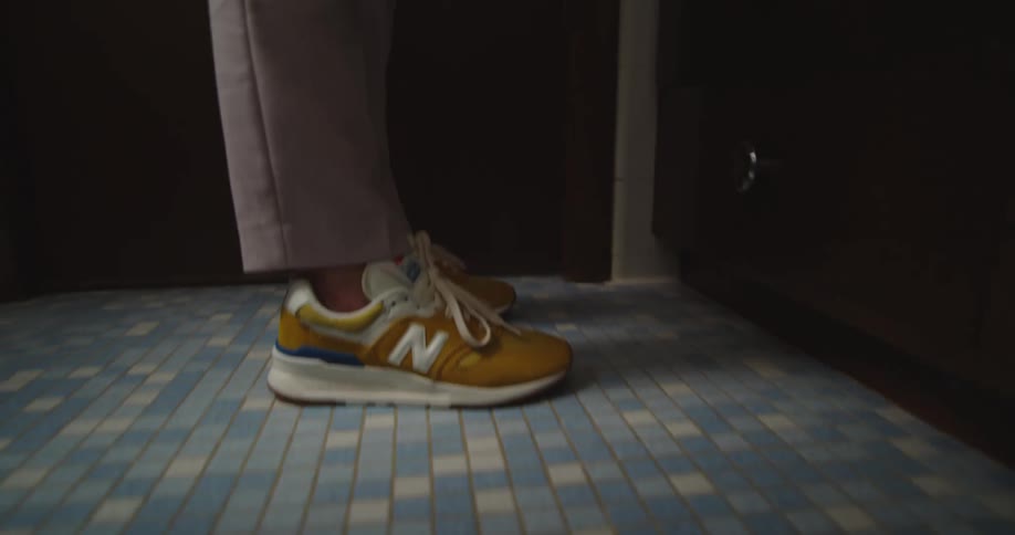 Young woman wearing a formal suit with colorful sneakers walks out of the bathroom