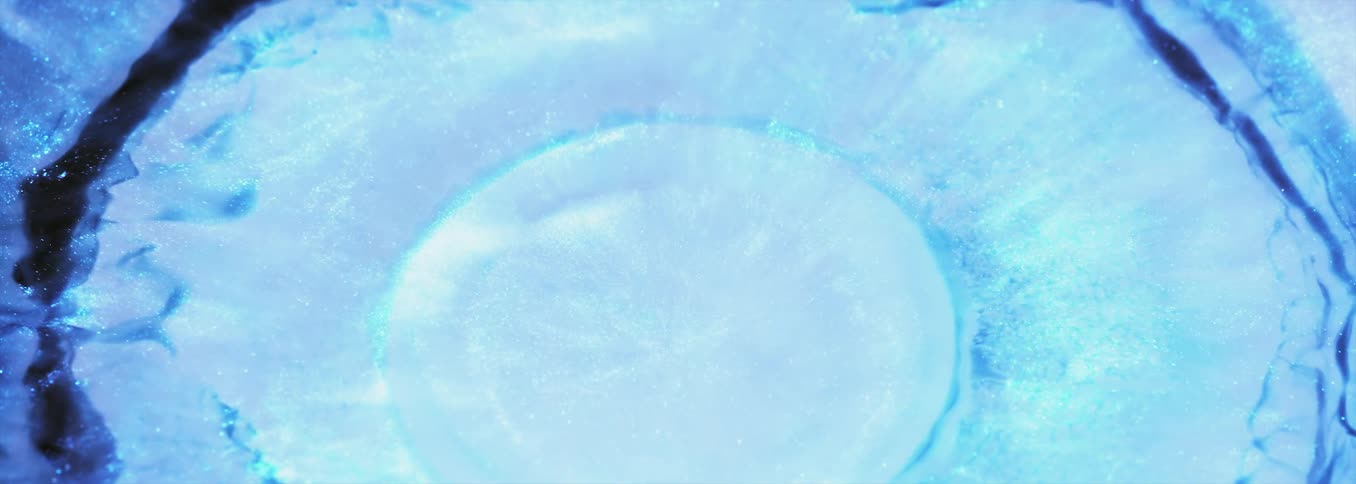 Drop of bright blue liquid ink splashes on a pool of white liquid