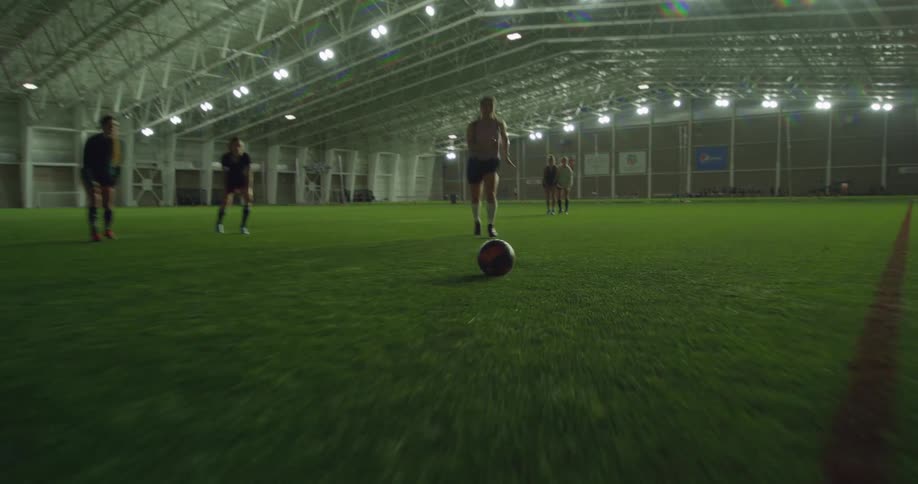 Young woman runs and kicks a soccer ball in a field at the stadium