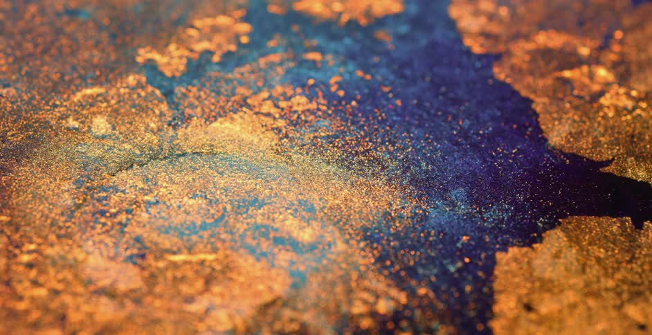 Golden particles floating on the surface of a deep blue liquid