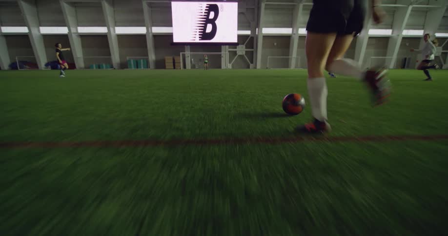 Woman playing soccer dribbles a player running for the goalpost