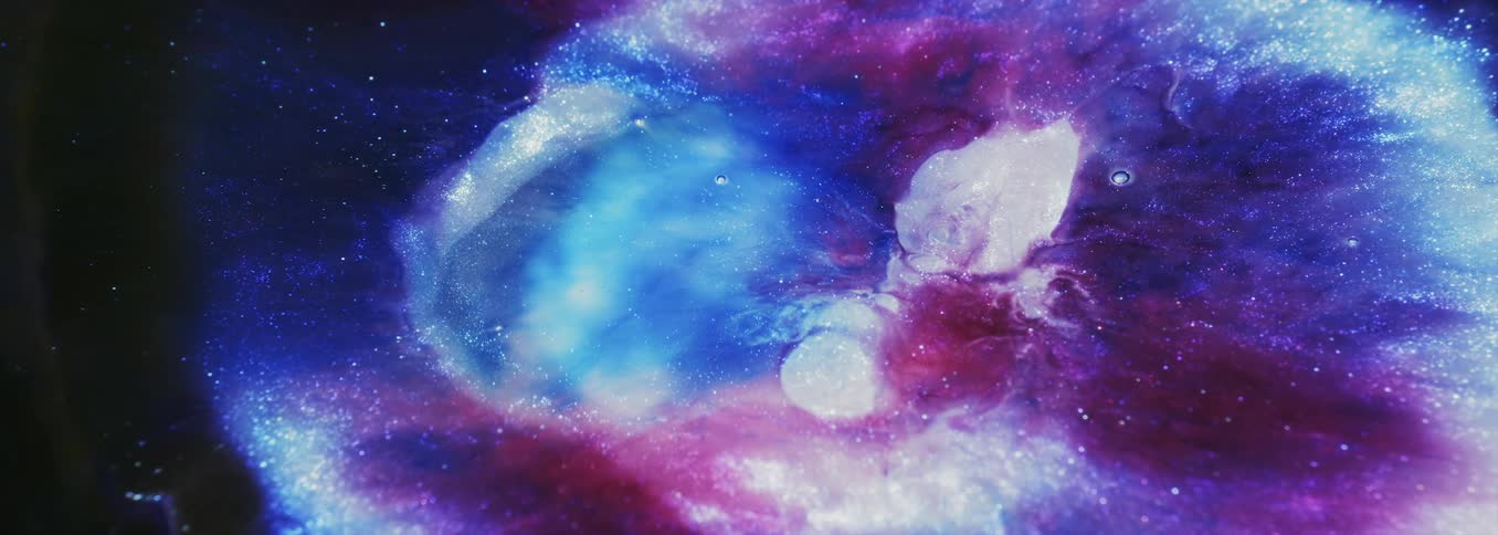 Black mix spreads out showing colorful multi hued mix as particles sparkle throughout