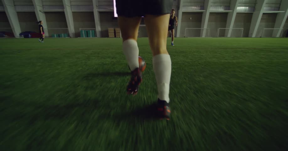Young female soccer playing runs kicking the ball on a stadium
