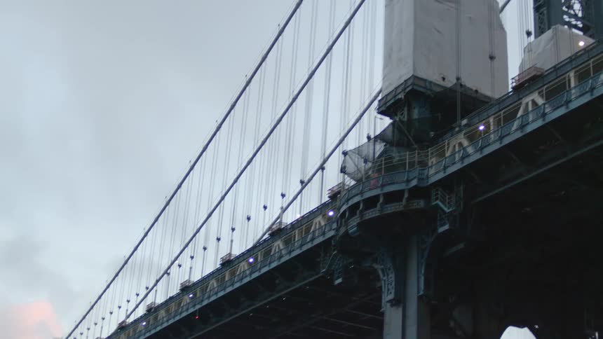 A large wire bridge is under the cloudy sky