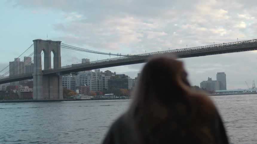 A woman looks at a city skyline from across the ocean