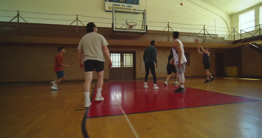 A group of men are playing basketball in a gym indoors