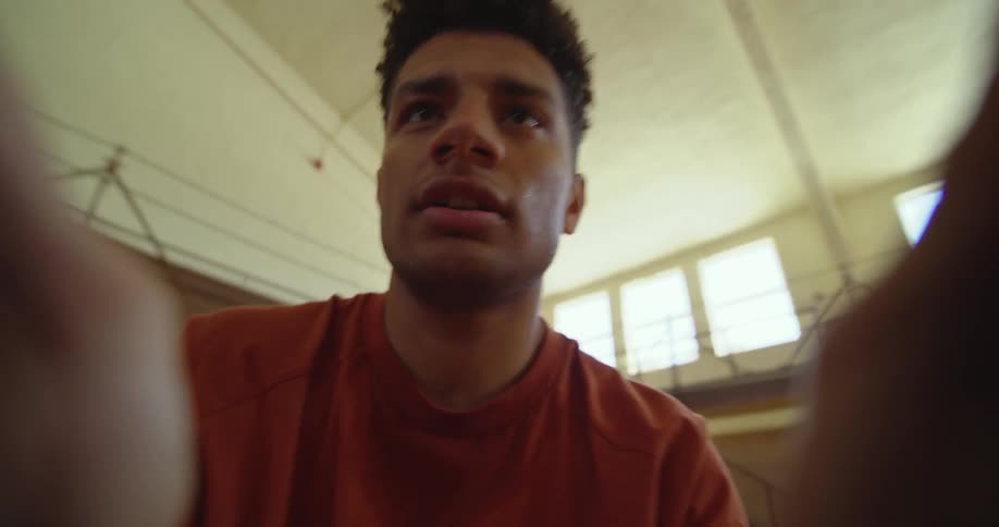 Young man holding a camera in his hands inside a basketball court
