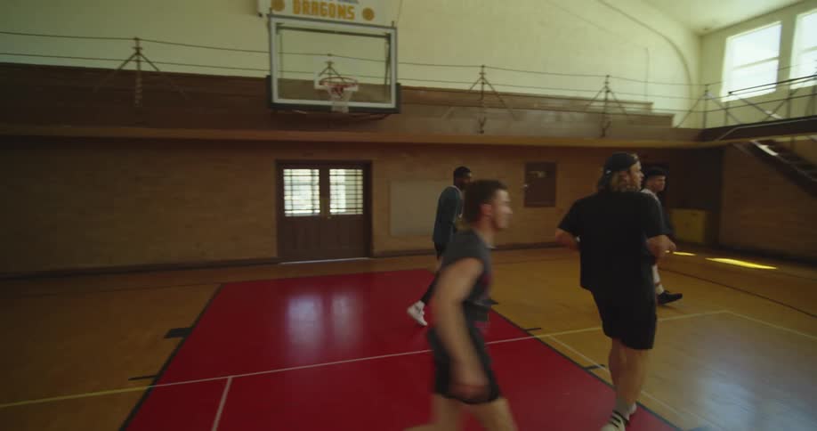 Men play basketball on basketball courtin empty gym