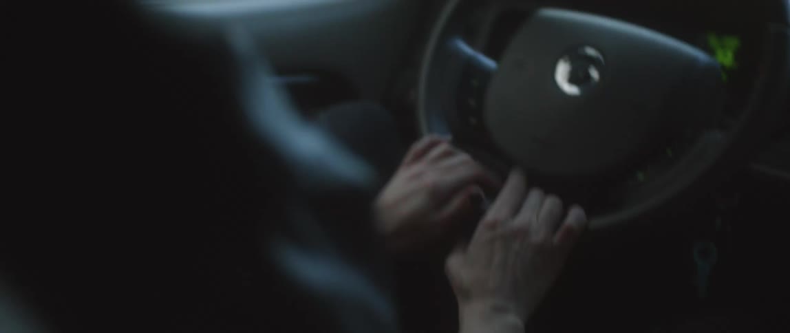 A woman taps her fingers while driving a car during the day