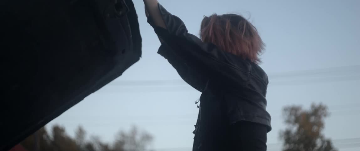 Woman lifts car hood and sighs as she examines engine