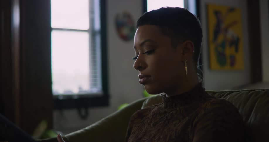 A young woman is sitting on the couch in the middle of the day