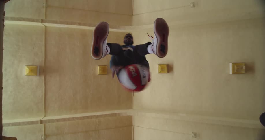 A youngblack man is dribbling a basketball inside of a building