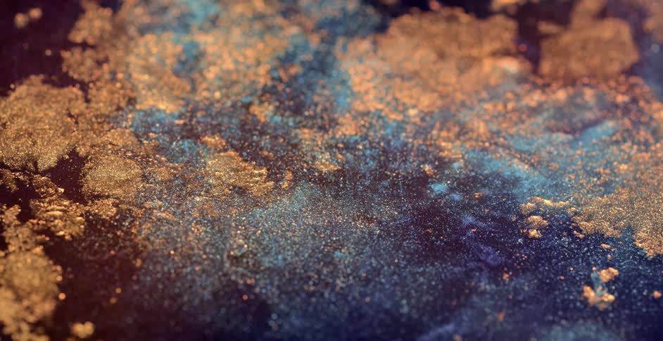 Abstract footage of gold flakes floating on water