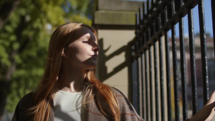 A woman touches the iron fences as she passes