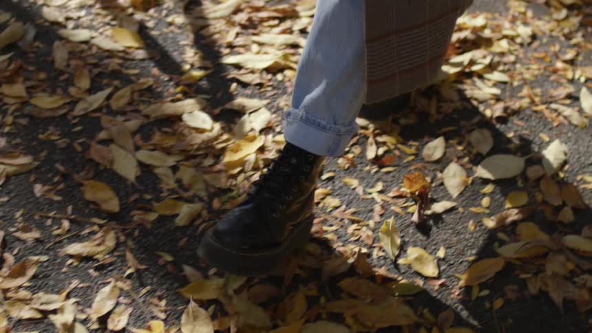 A person walks through the fallen leaves