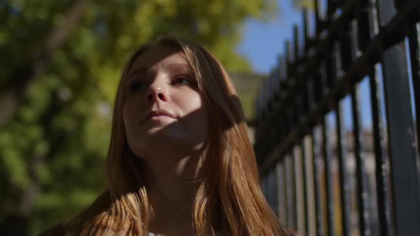 A woman is walking past the tall fence