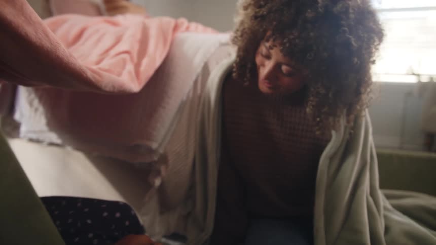 Mother and daughter playing on a makeshift blanket fort at home