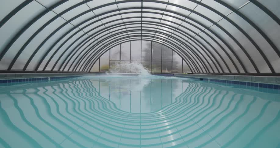 A large man dives into an indoor swimming pool