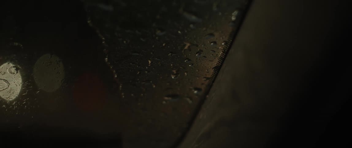 Close up of water droplets on the windshield of a moving car at night