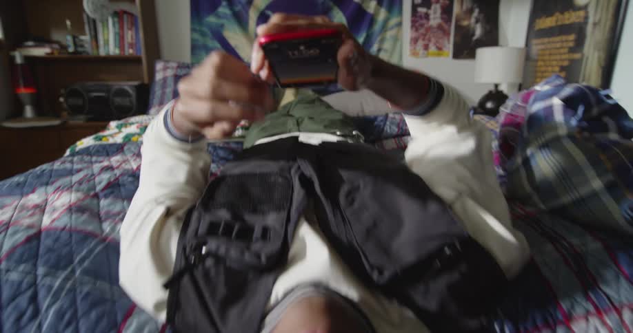Dynamic footage of a young man resting on a bed looking at his phone
