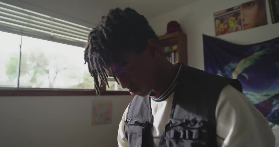 Young man sitting on the bed at home reading on his phone