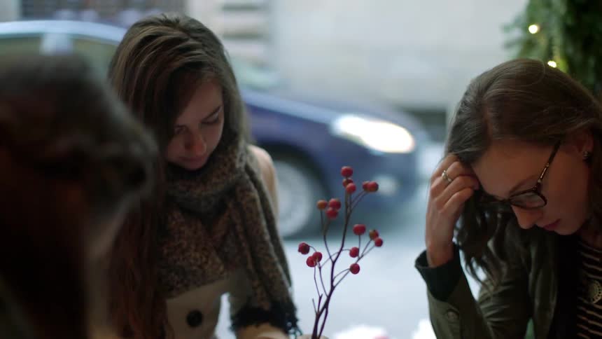 Three woman sit at a table and read