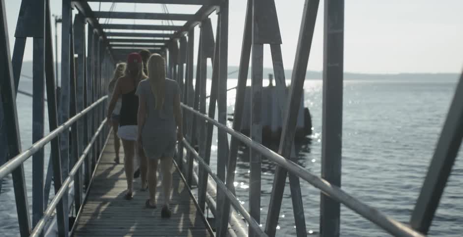 Girls walking along pier at the water