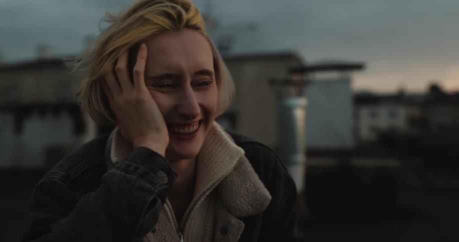 Two women laugh while sitting on their building rooftop