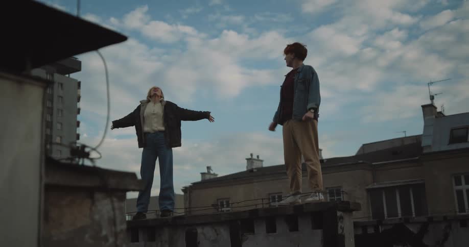 Two people are standing on the ledge and screaming on the top of there lungs