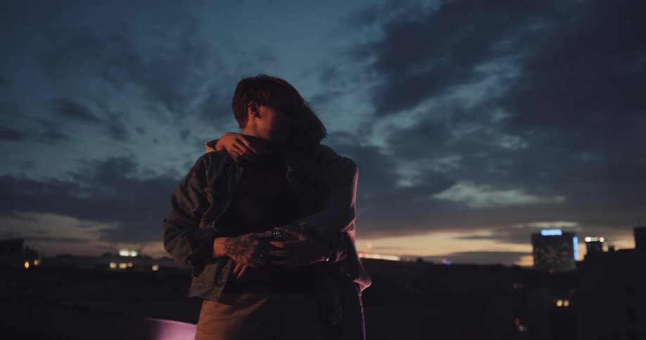 Happy couple dancing and hugging on the roof of a building at evening