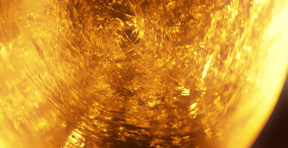 A gold shimmering fluid spins in a spiral pattern