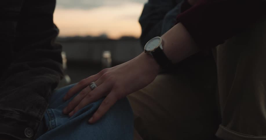 Lesbian couple touches each other and holds hands outdoors at dusk