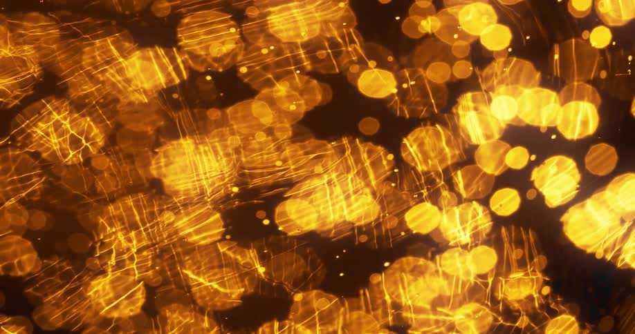 Golden spots flow under surface as transparent lines pass over head in mixture