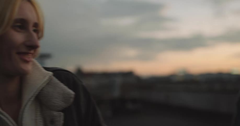 Young couple looking at each other lovingly on the roof of a building at evening